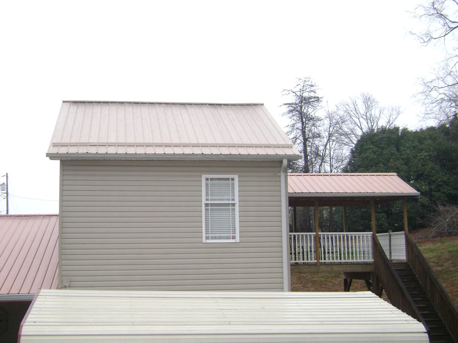 Tan metal roofs on a two story addition and attached porch, from a Roof Replacement job in Willow