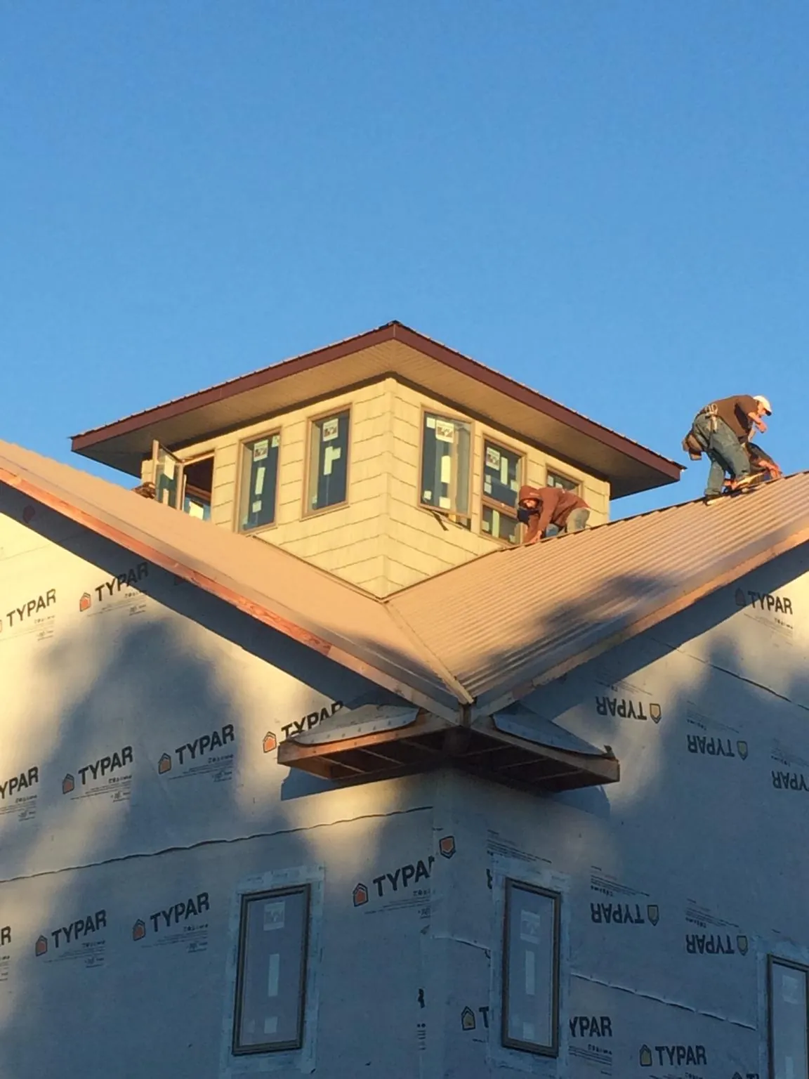 Roofers working around a rooftop cupola on a new metal roof at sunset — Roof Waterproofing in Willow by Roofing Brothers